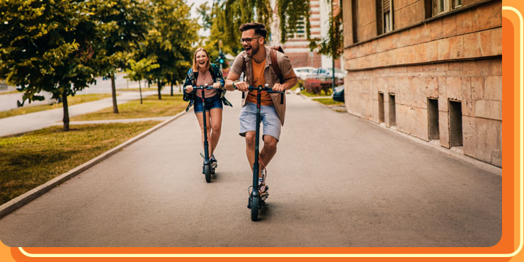 Happy friends riding electric scooters in the city