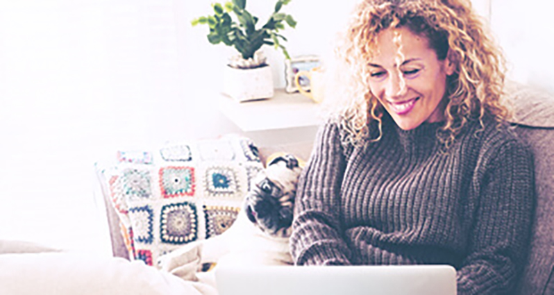 Woman sitting on a couch with a blanket and her dog