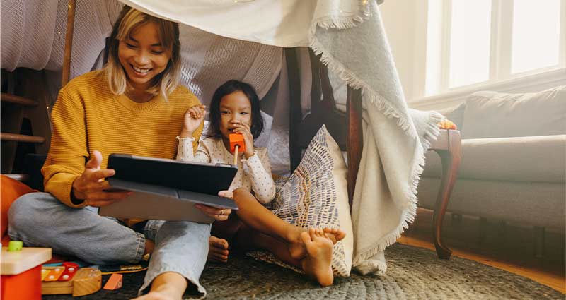 Mother and daughter playing with tablet at home