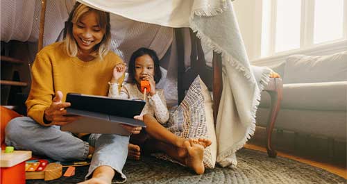 Mother and daughter playing with tablet at home