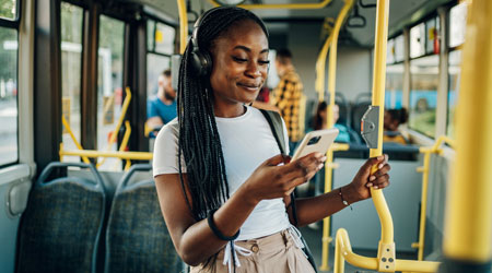 Young black woman on bus looking at smartphone